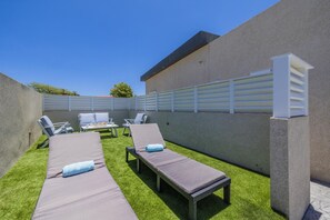Eine Dachterrasse mit zwei Liegestühlen, einem Tisch und Stühlen.