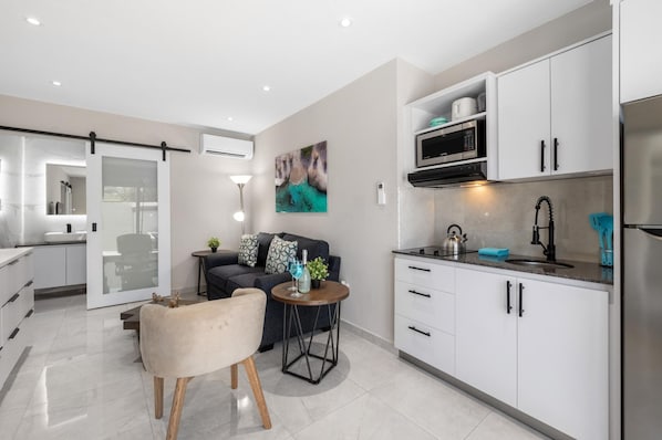 A modern kitchen with white cabinets, a black countertop, and a stainless steel refrigerator.
