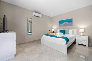 Ein modernes Schlafzimmer mit einem Bett, Nachttischen, einem Fernseher, einem Spiegel und einer Klimaanlage.