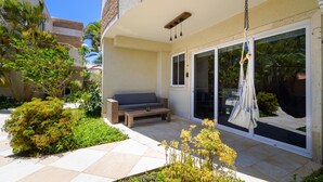 Une terrasse avec un canapé, un fauteuil suspendu et une petite table.