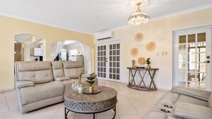 Una sala de estar con un sofá color beige, una mesa de centro redonda y una araña.