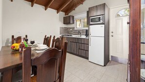 Una cocina con una mesa de comedor, sillas, un refrigerador, un microondas y un lavaplatos.