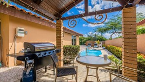 Un patio exterior con una parrilla, una mesa y una piscina.