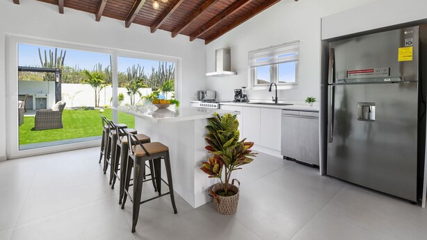A modern kitchen with a large island, stainless steel appliances, and a view of a garden. - 2BR Countryside Home w Sea Views Private Pool (Noord)