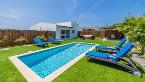 A backyard with a swimming pool, blue lounge chairs, and a wooden fence. - 2BR Countryside Home w Sea Views Private Pool (Noord)