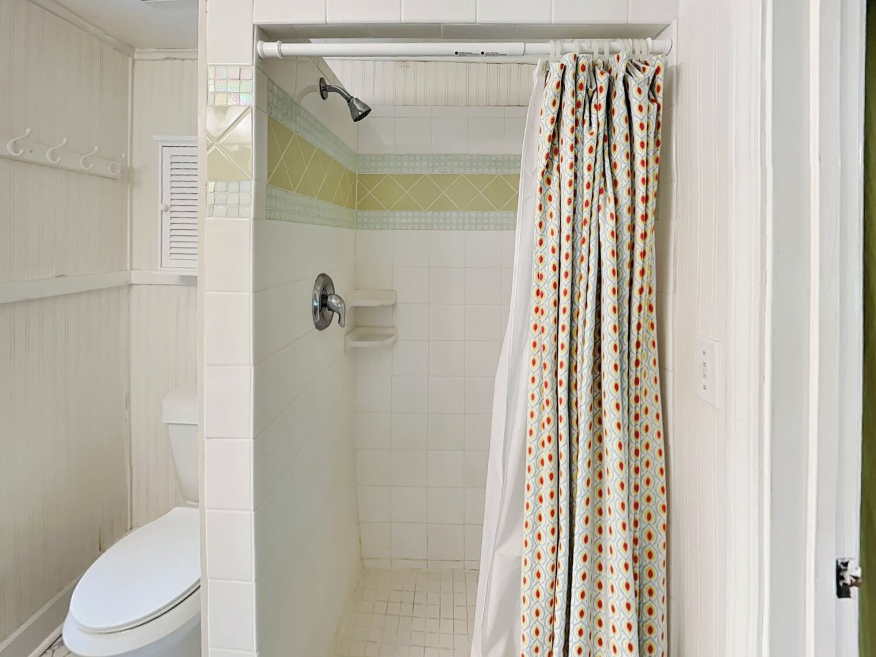 Baño con ducha, inodoro y cortina de ducha estampada.