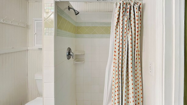 Ein Badezimmer mit Dusche, Toilette und einem waschraum-Vorhang mit Muster.