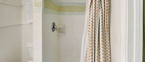 Baño con ducha, inodoro y cortina de ducha estampada.