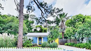 A house with a blue door, surrounded by a white picket fence, and various trees and plants. - A Shore Thing by Tybee Vacation Rentals (Tybee Island)