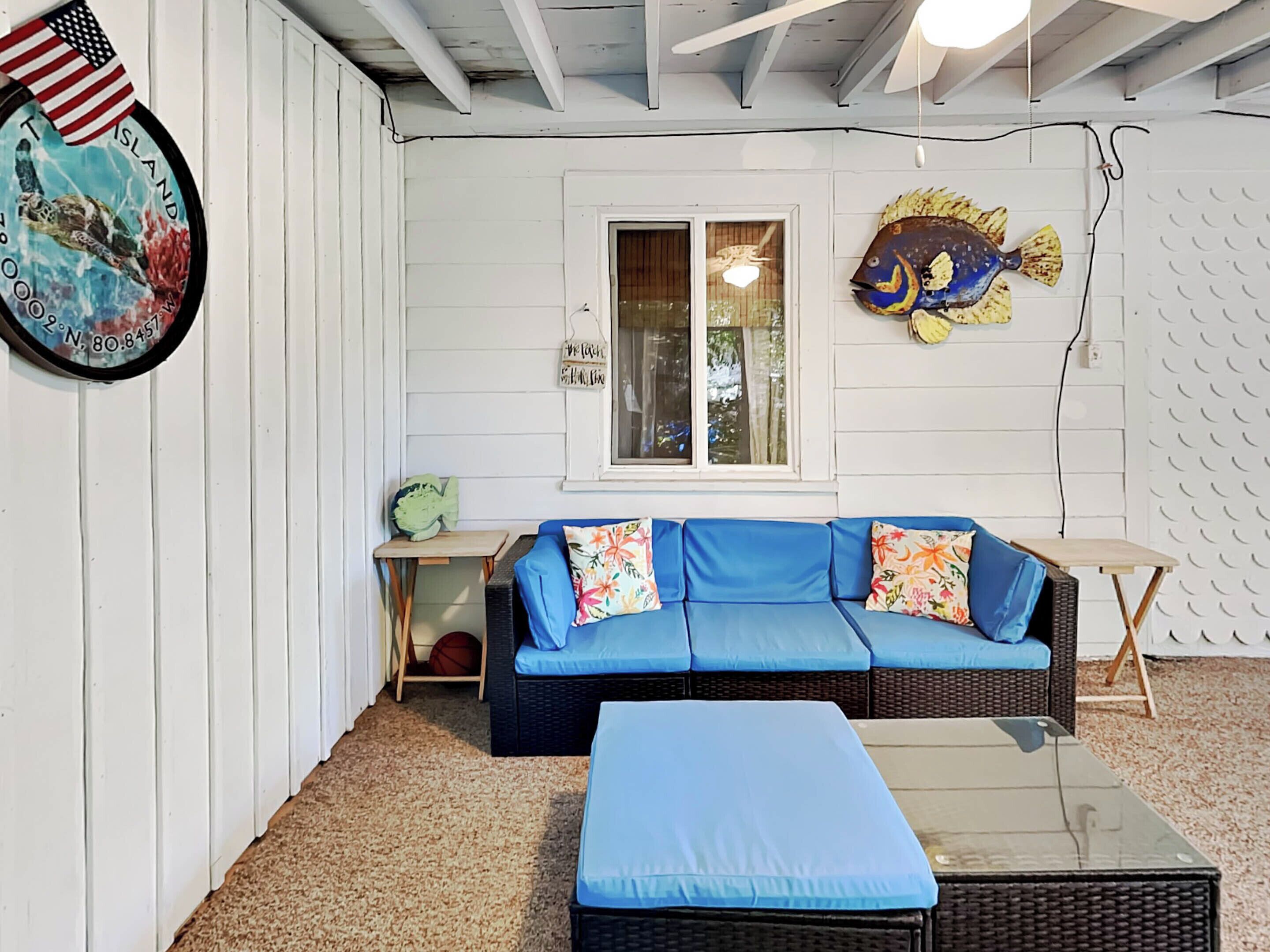 A cozy room with a blue sofa, a small table, and a fish decoration on the wall.
