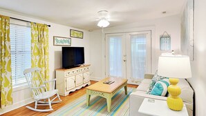 A living room with a television, a rocking chair, a coffee table, and a sofa. - A Shore Thing by Tybee Vacation Rentals (Tybee Island)