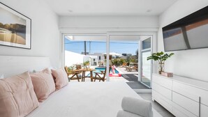 Ein modernes Wohnzimmer mit einer Couch, einem Fernseher und Blick auf einen Außenpool.