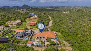 An aerial view of a resort with multiple buildings, a swimming pool, and a large natural landscape. - Breezy Cozy Retreat Arikok National Park Pool (Santa Cruz)