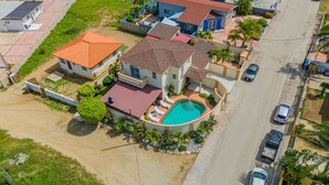 A residential area with houses, a swimming pool, and parked cars.