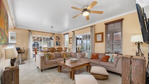 A spacious living room with a large sofa, a wooden coffee table, and a ceiling fan.