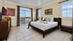 A bedroom with a large bed, a dresser, a desk, and a window with curtains.
