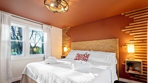 A neatly arranged bedroom with a large bed, white linens, a bedside table with a lamp, and a view of trees through the window. - Creekside Cabin: Hot Tub, Cinema, EV Charger, Dogs (Luray)