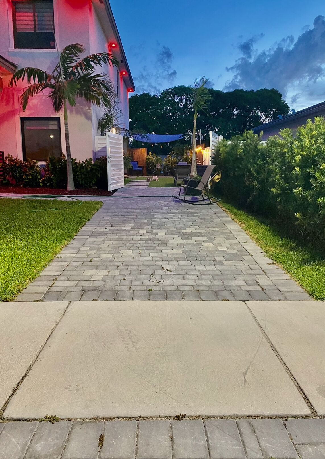 A paved pathway leading to a building with a covered outdoor seating area.