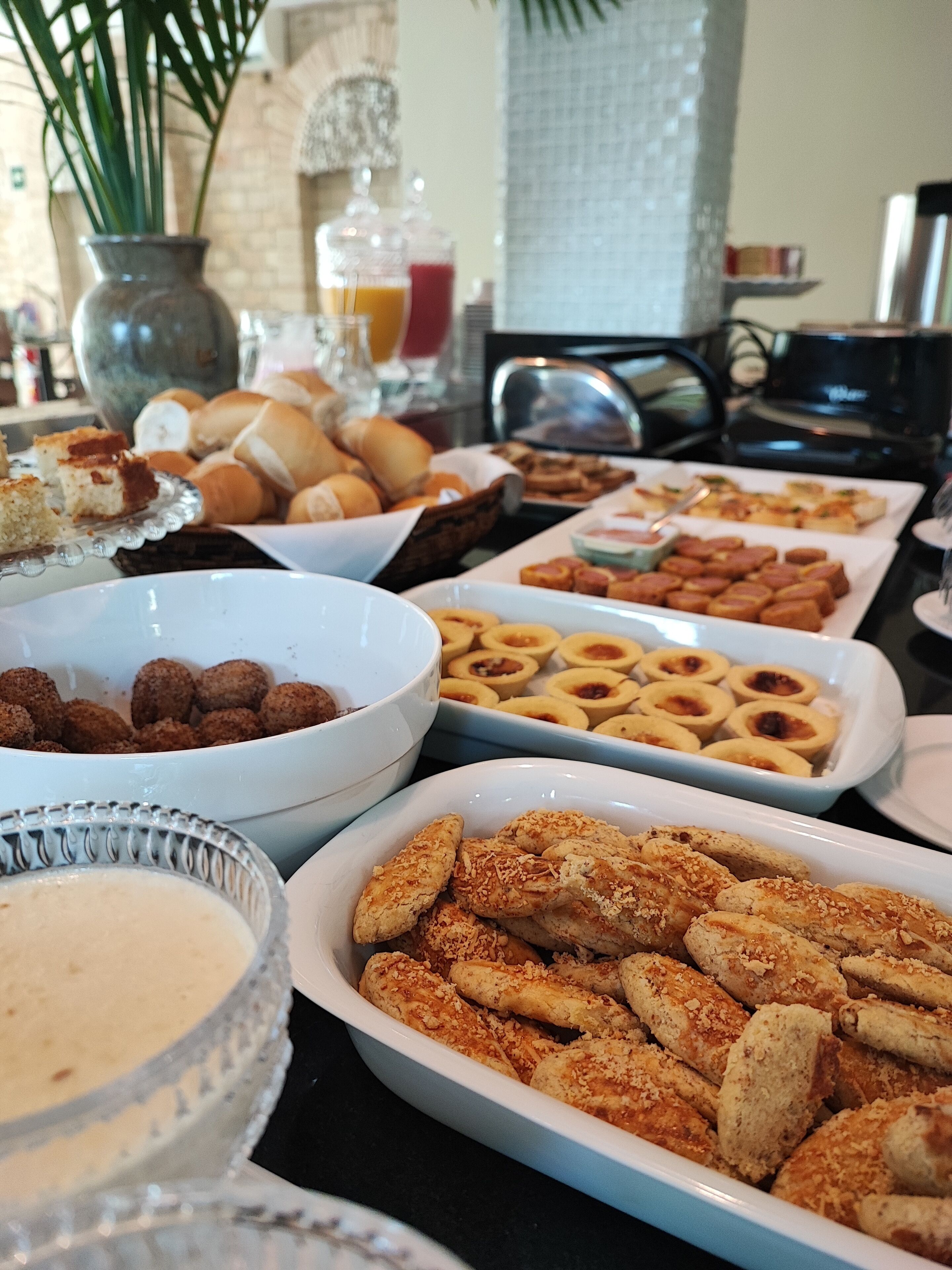 Una mesa de buffet con diversos alimentos, incluyendo pasteles, pan y un tazón de sopa.