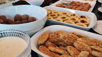 A buffet table with various food items including pastries, bread, and a bowl of soup.