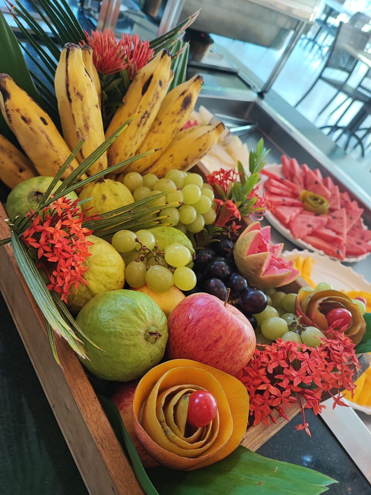 A fruit and flower arrangement on a wooden table.