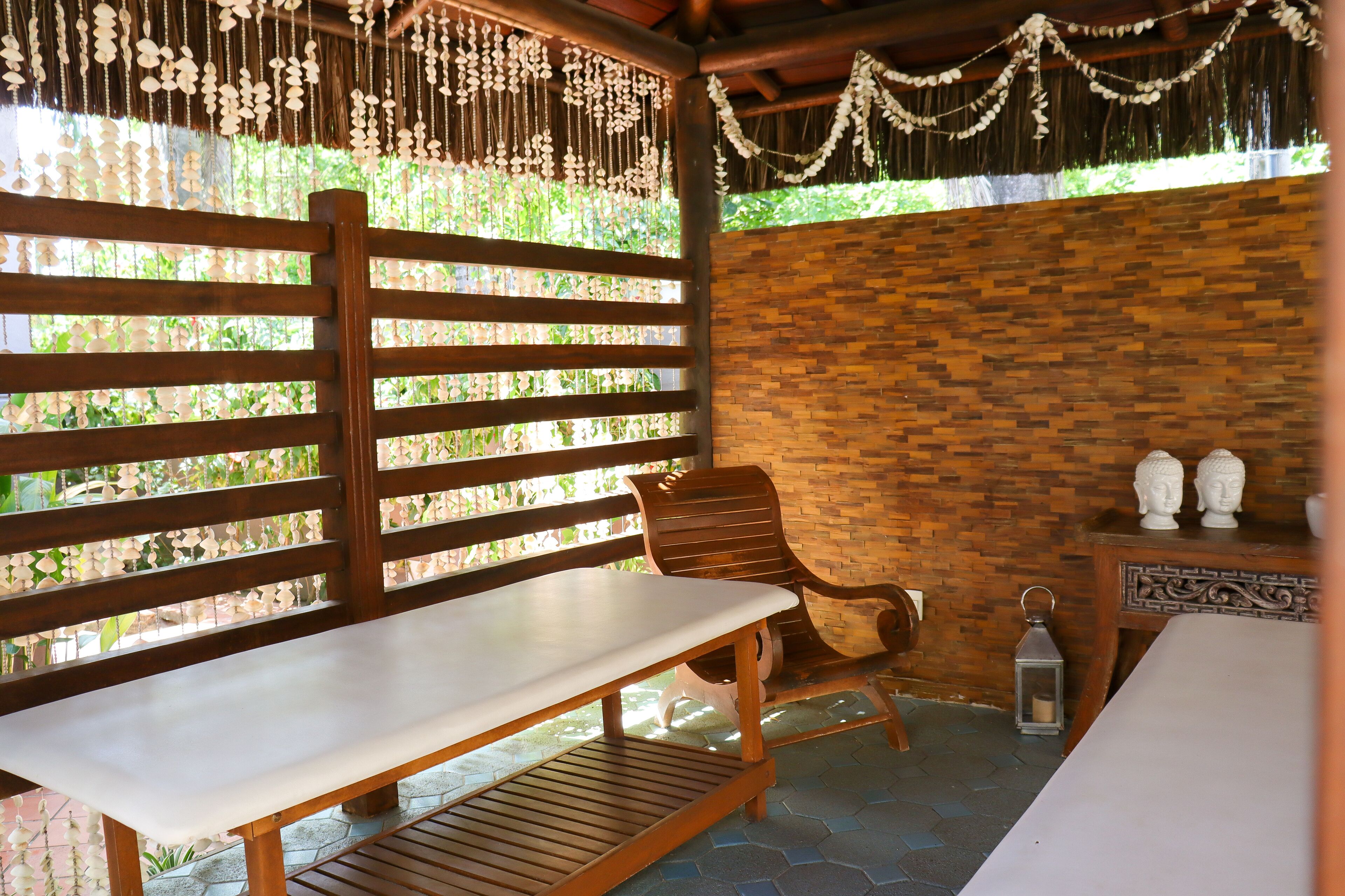 A wooden bench and table set against a brick wall with a hanging decorative string.