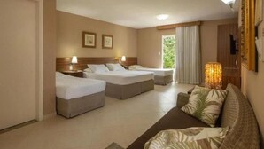 A hotel room with two single beds, a sofa, a lamp, and a window with curtains. - Hotel Coral Beach  (Tamandaré)