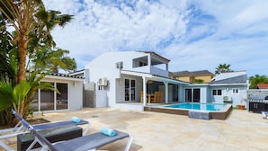 Une maison moderne dotée d’une piscine, de chaises longues et d’un espace patio.