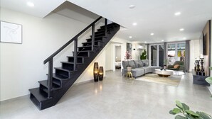 Un salon moderne avec un escalier, un canapé gris et une table basse.