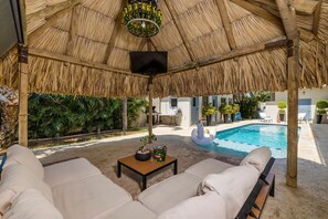 Un espacio exterior cubierto con piscina, sillas de descanso y una mesa con plantas.