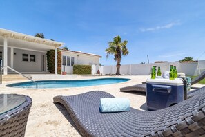 A pool area with lounge chairs, a cooler, and a house in the background. - 4br4ba w Private Pool Walking Distance to Ritz (Noord)