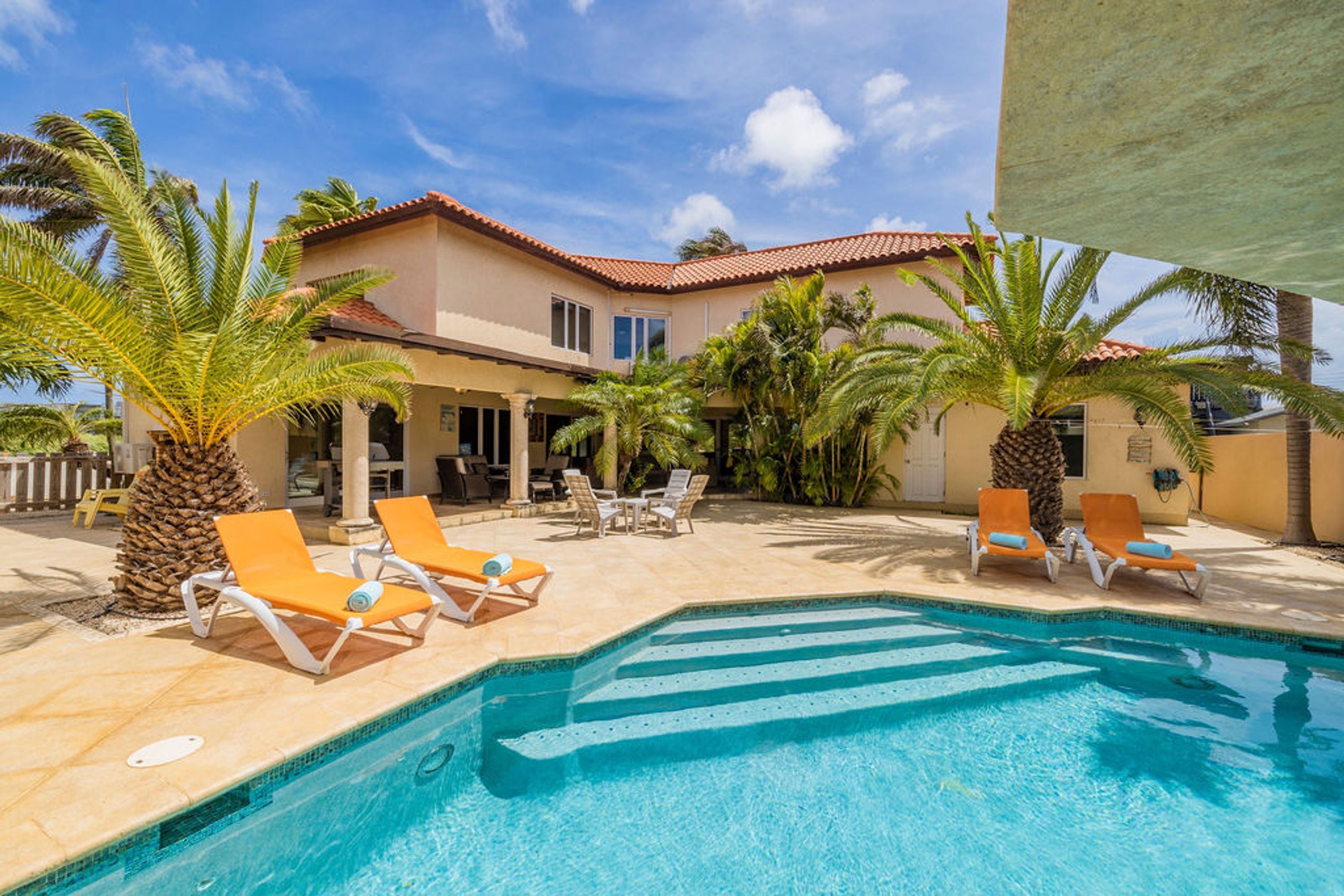 A pool area with lounge chairs and palm trees.