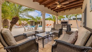 An outdoor patio with wicker furniture, a ceiling fan, and a pool in the background. - Amazing 4br4ba Villa w Pool Birdsanctuary Views (Noord)