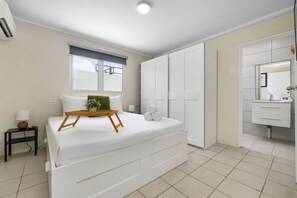 A bedroom with a bed, bedside table, and a window with blinds.