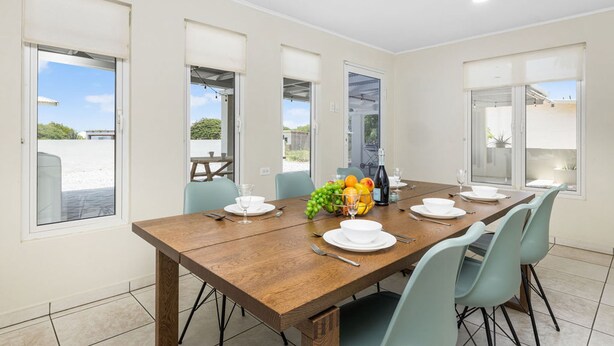 A dining area with a wooden table set for four, light blue chairs, and a fruit bowl on the table. - Lovely 3br2ba w Wifi Parking in Central Location (Paradera)