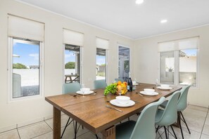A dining area with a wooden table set for four, light blue chairs, and a fruit bowl on the table. - Lovely 3br2ba w Wifi Parking in Central Location (Paradera)