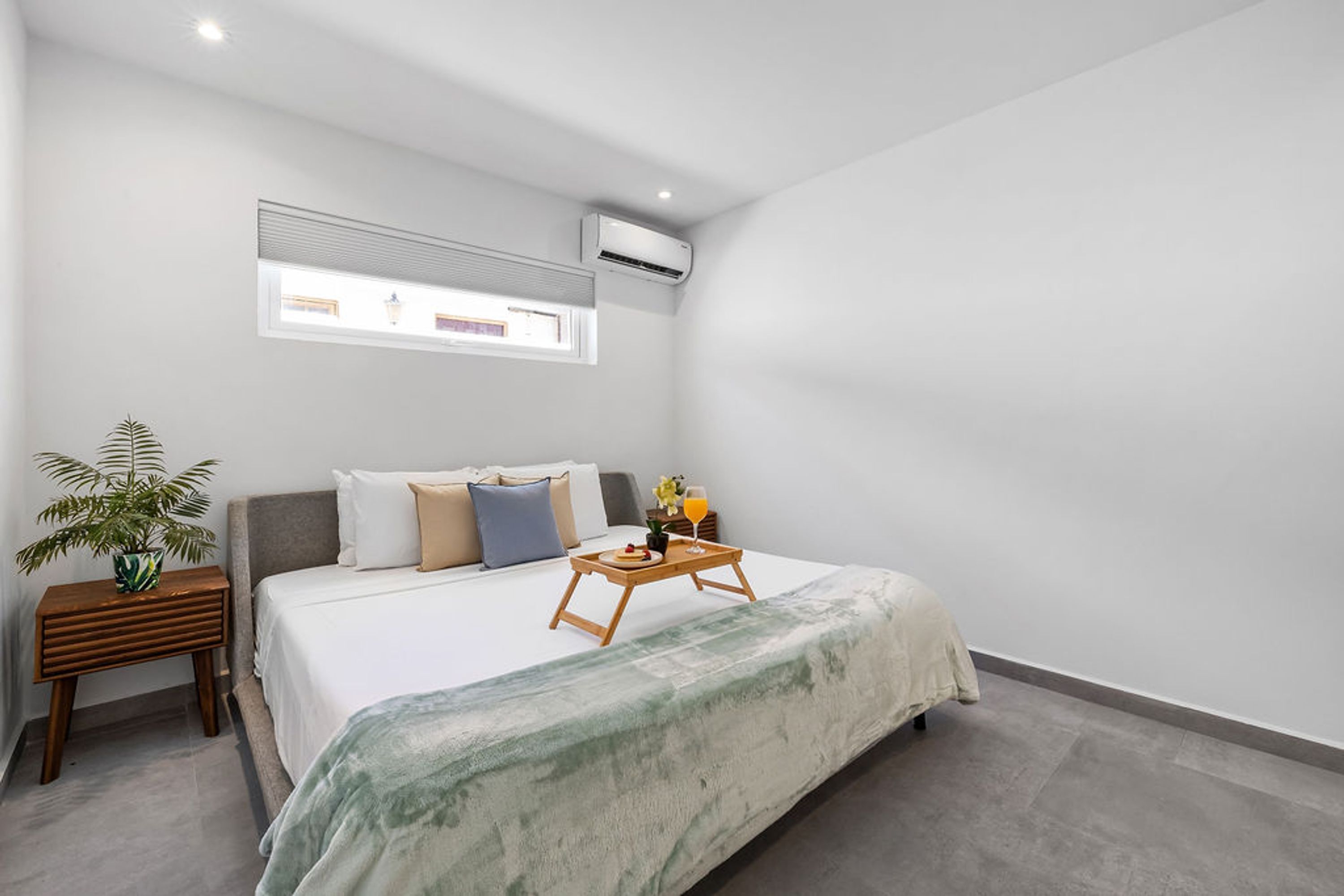 A modern bedroom with a bed, bedside table, and a small window.