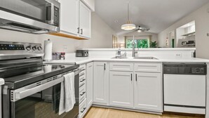 A modern kitchen with white cabinets, stainless steel appliances, and a built-in dishwasher.