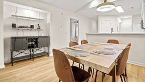 A modern dining area with a wooden table, six chairs, and woven placemats.