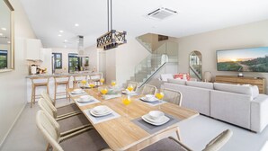 Una cocina moderna con comedor, una escalera y una sala de estar con televisor.