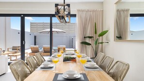 Comedor con una mesa de madera dispuesta para seis personas, rodeado de sillas de mimbre.
