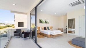 Un dormitorio moderno con una cama grande, un balcón con asientos y vistas al paisaje.