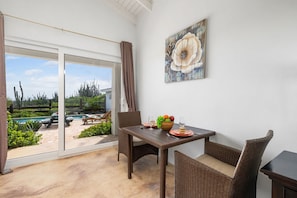 A dining area with a table, chairs, and a view of a pool and garden.