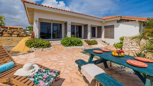 A house with a patio, a dining table set with plates, and a pool area. - Tropical Getaway Near Arikok National Park Pool (Santa Cruz)
