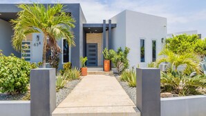 Edifício moderno com um caminho de concreto que leva a uma porta com a inscrição '63A'.