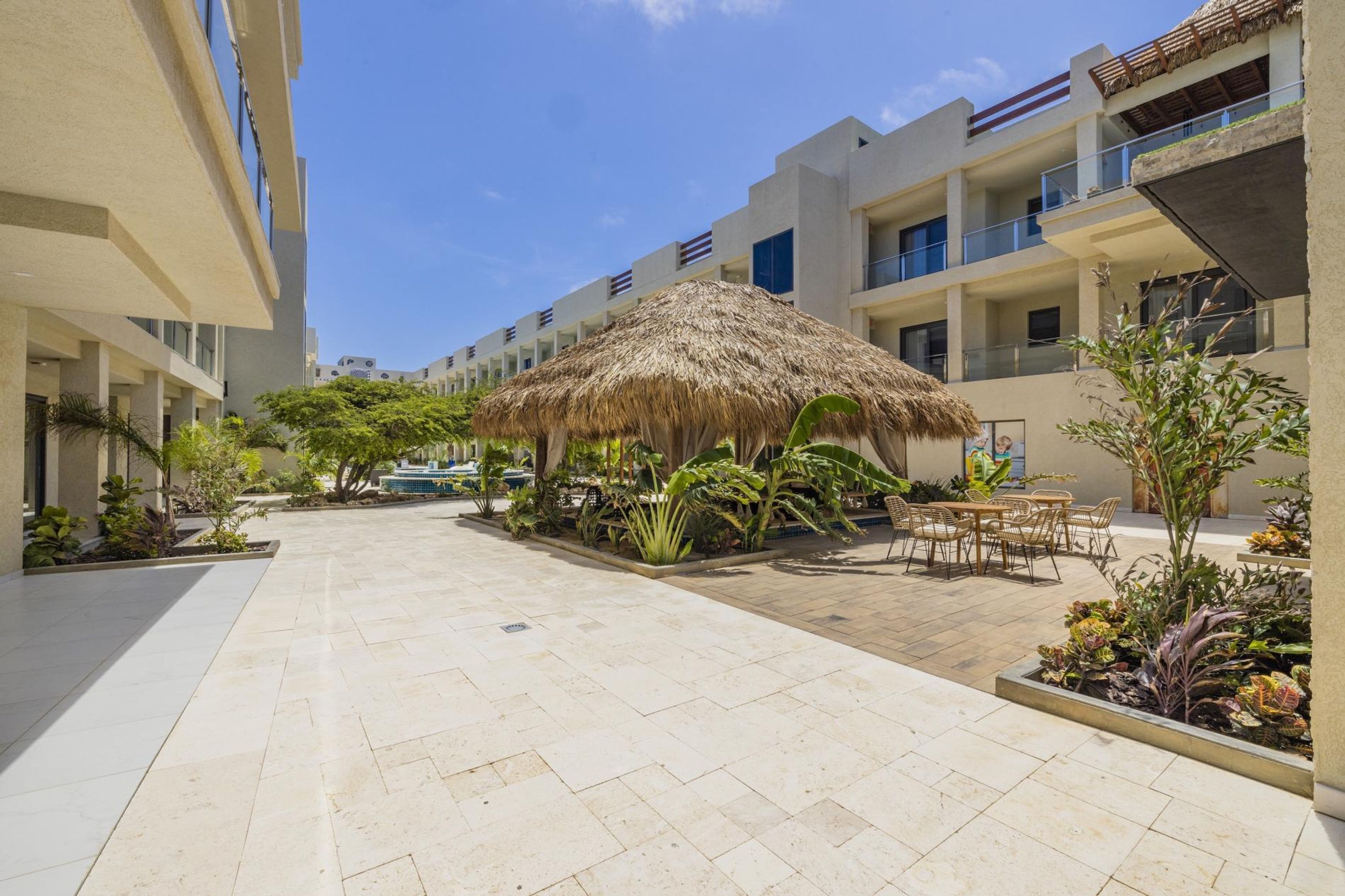A courtyard with a thatched-roof structure, outdoor seating, and a pool.