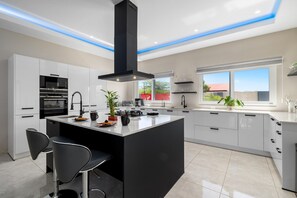 Une cuisine moderne dotée d’un îlot central, de meubles blancs et d’une hotte noire.
