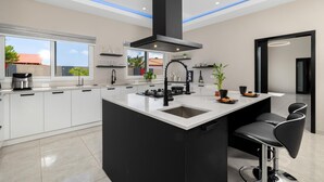 A modern kitchen with a large island, black cabinetry, and a sleek black range hood.