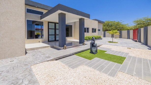 A modern building with a covered patio area, outdoor seating, and a decorative fountain.