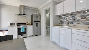 Una cucina moderna con mobili bianchi, elettrodomestici in acciaio inossidabile e uno schienale piastrellato.